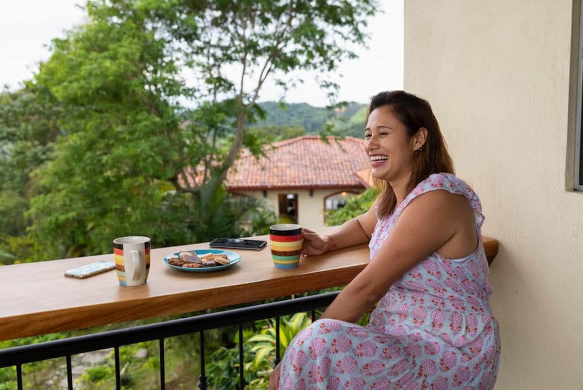 Una mujer latina sonriente trabaja de forma remota desde el porche de su casa.