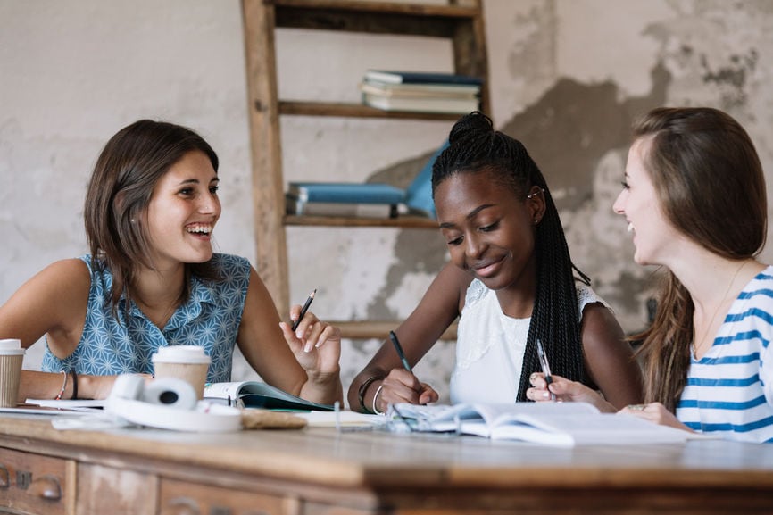 Cheerful multiethnic female students talking And Writing