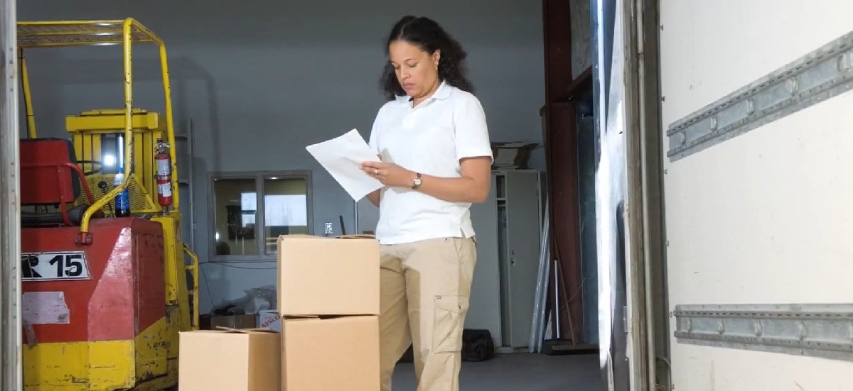 a warehouse worker checks her paperwork