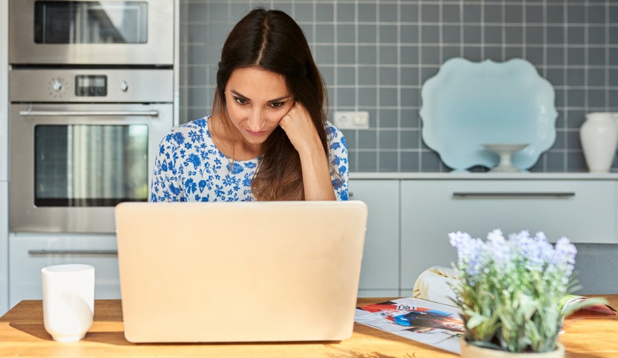 一个女人在厨房桌子上用笔记本电脑工作