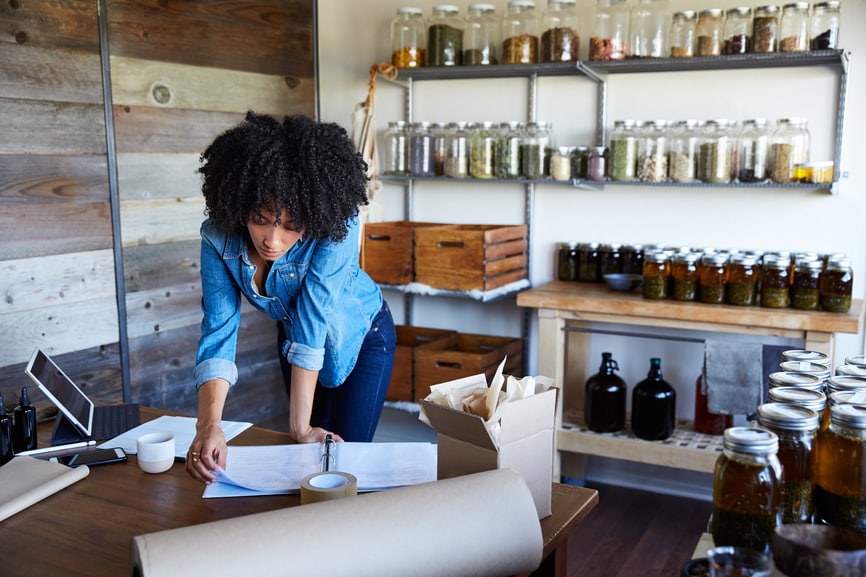 woman working at desk with paperwork and jars on shelves