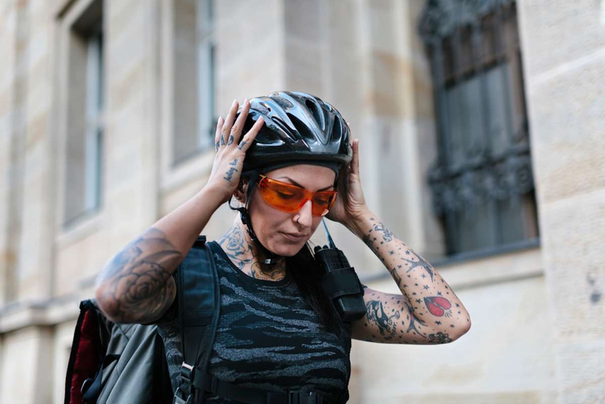 Female bicycle messenger puts on her bike helmet
