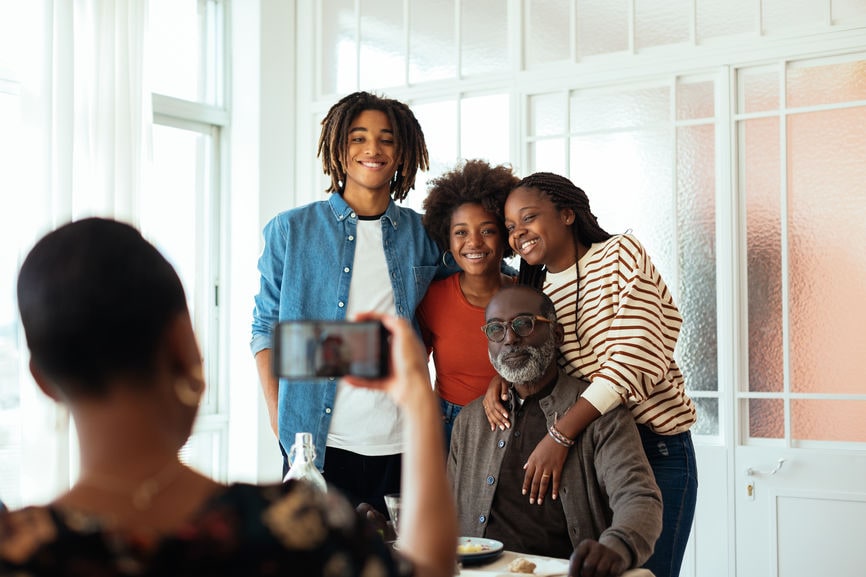 Woman taking a photo of her children with grandfather.