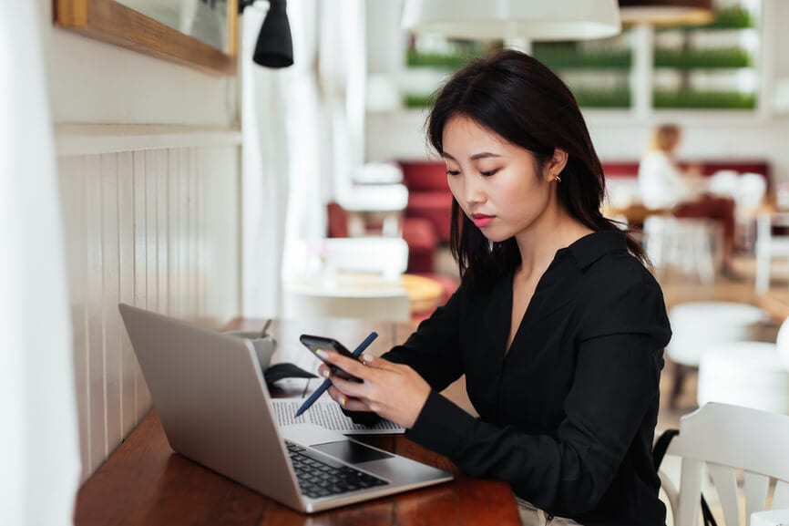 A woman in a café on her laptop researching ways to lower her tax rate