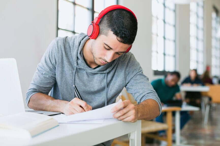 一名戴着耳机的大学生在图书馆工作