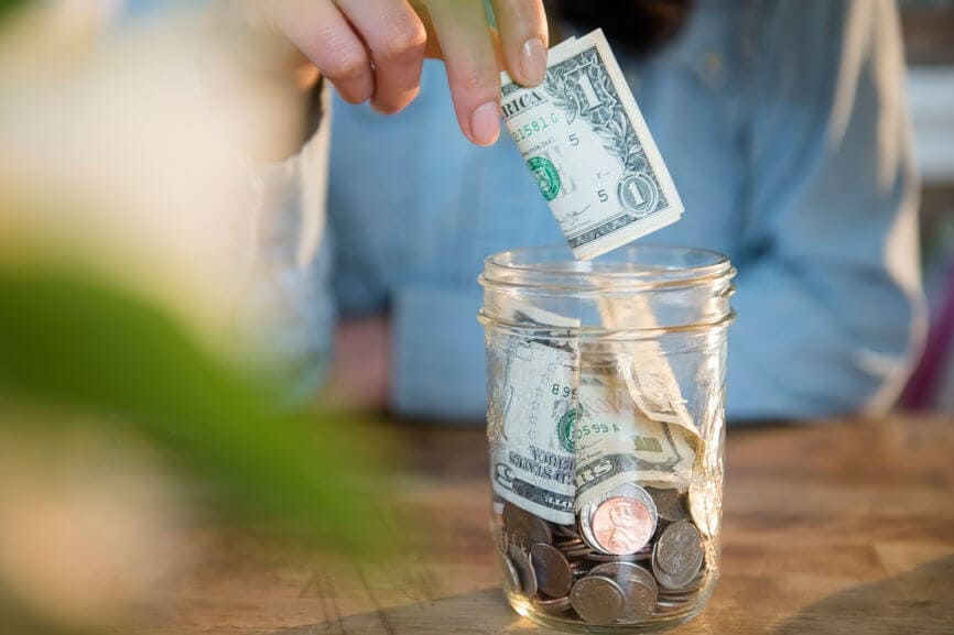 someone putting money in a money jar