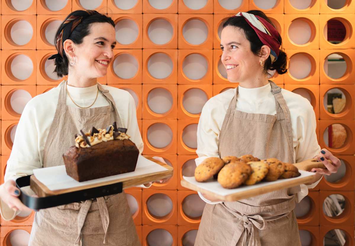 Smiling bakers holding cookies and a cake