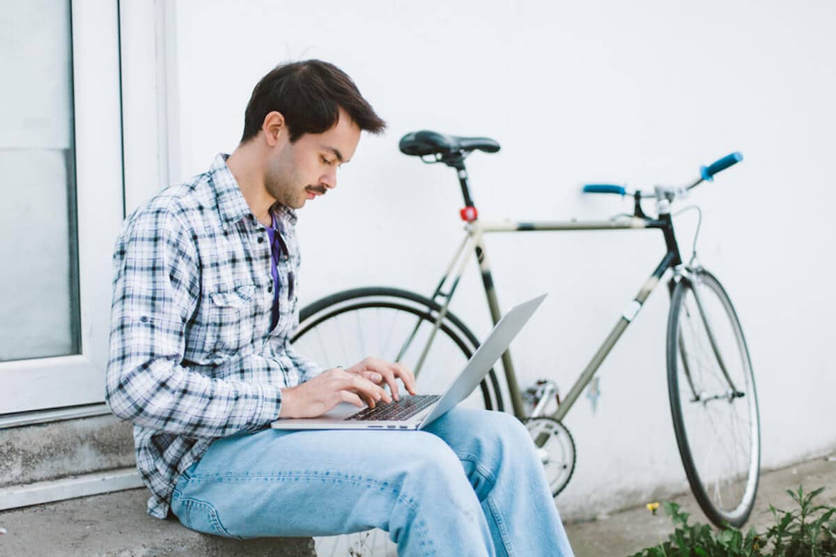 一个男人坐在外面用笔记本电脑打字