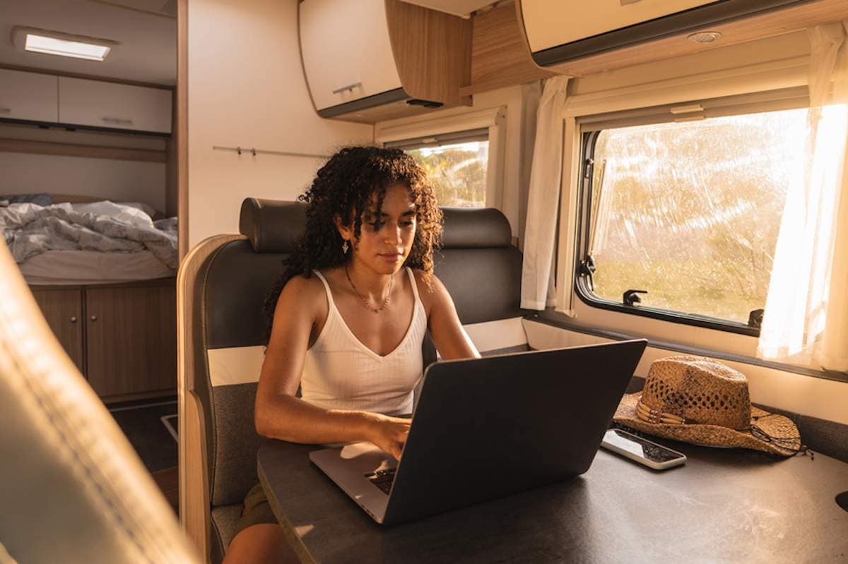 Young woman using her laptop at table in a recreational vehicle