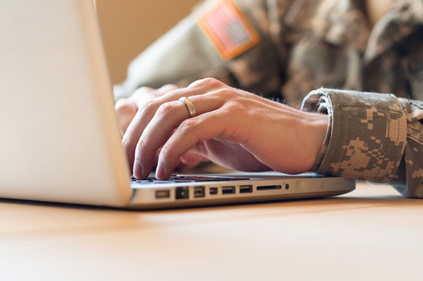 Man in military uniform typing on a keyboard