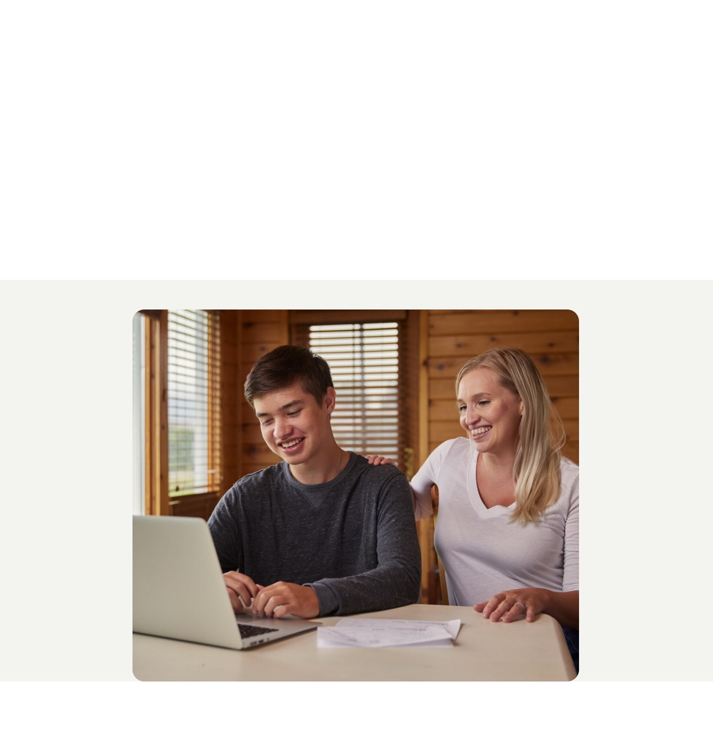 A mother and son are seated at a table, filing their taxes with TurboTax on their laptop.
