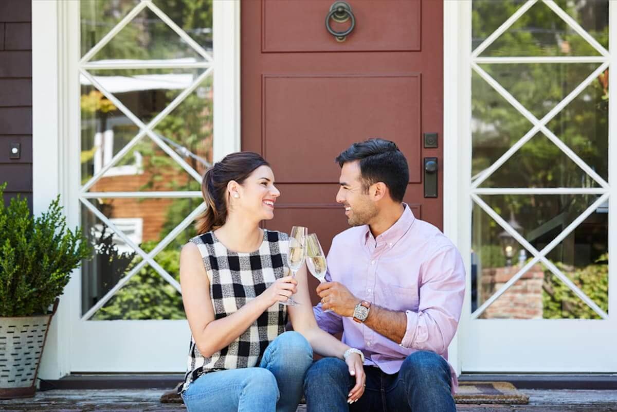 A young couple celebrates their home purchase with a champange toast.