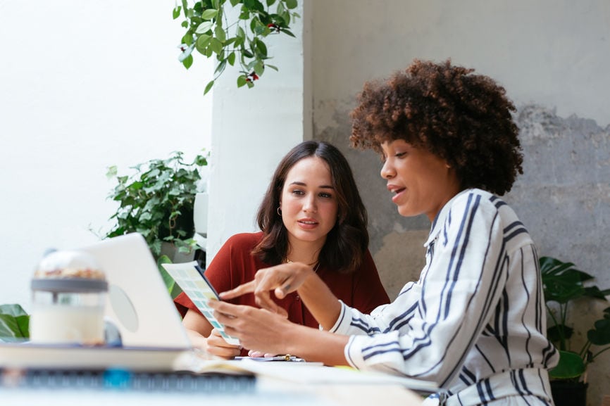 Two self-employed women reviewing health insurance premiums together.