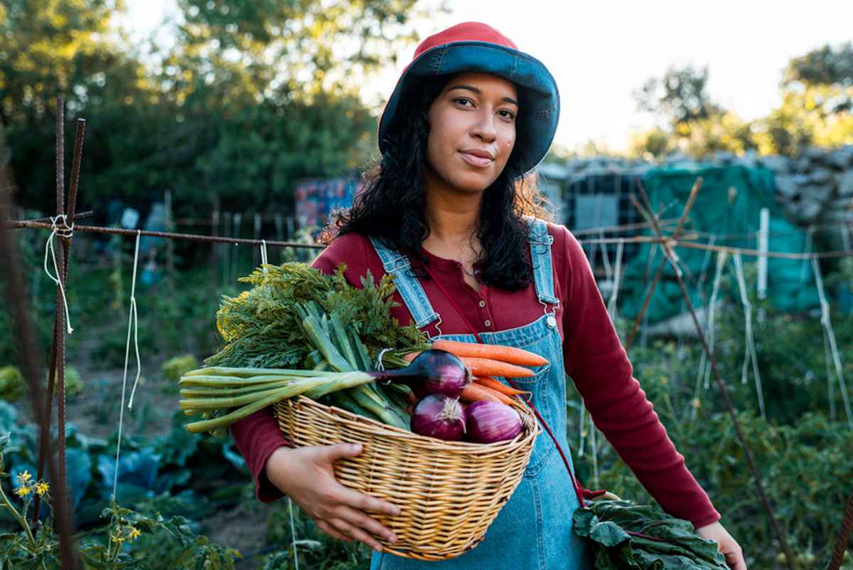 A woman holds a basket of produce harvested in her garden.