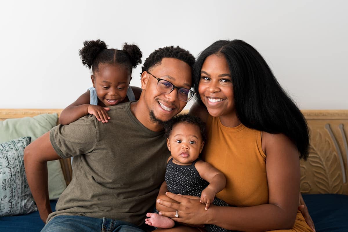 A smiling Black family of four poses for a photo.