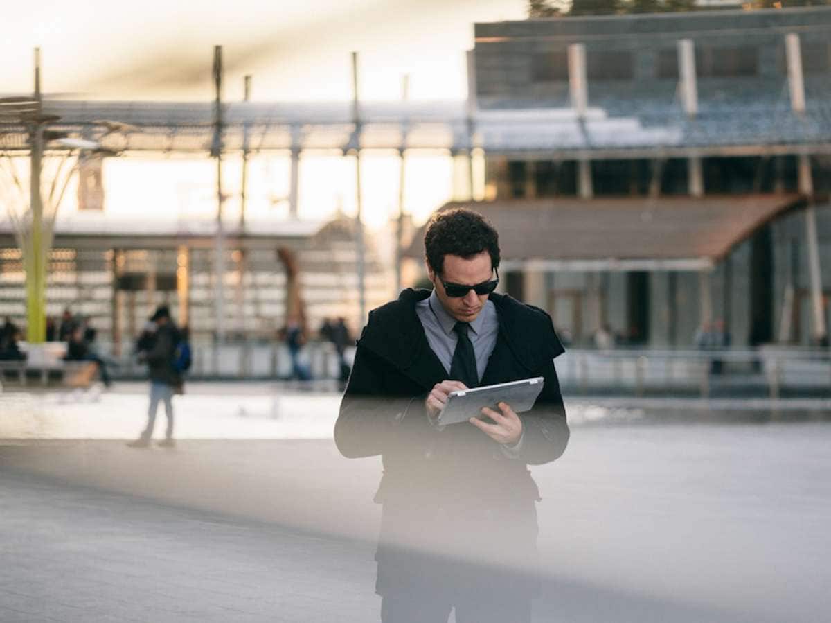 Young businessman wearing sunglasses uses a tablet in a financial district