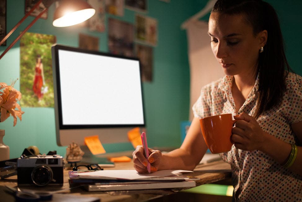 Woman drinking coffee at her desk and investing her tax refund.