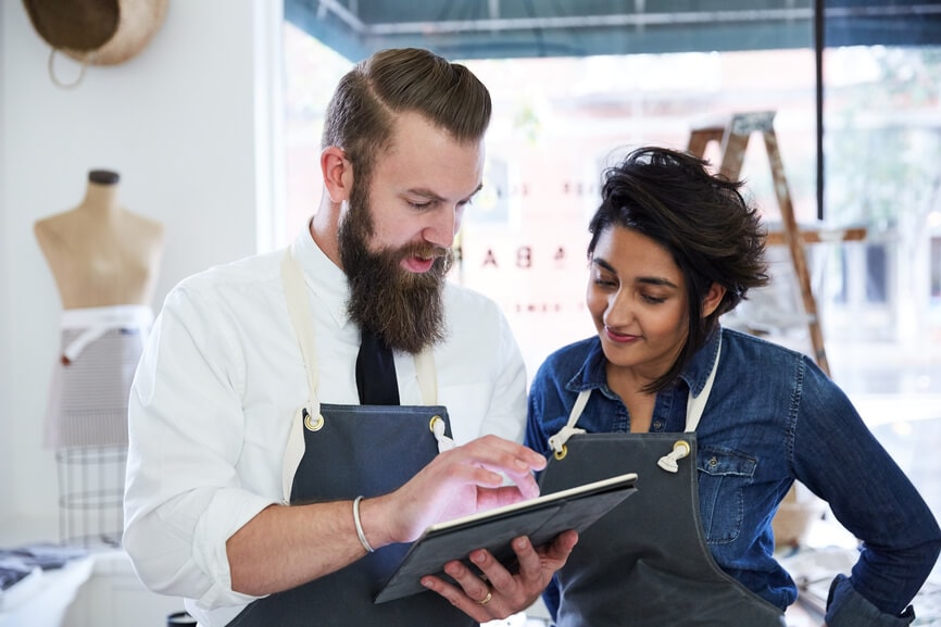 Shop owner and employee discuss the W-4 tax form changes on an iPad.