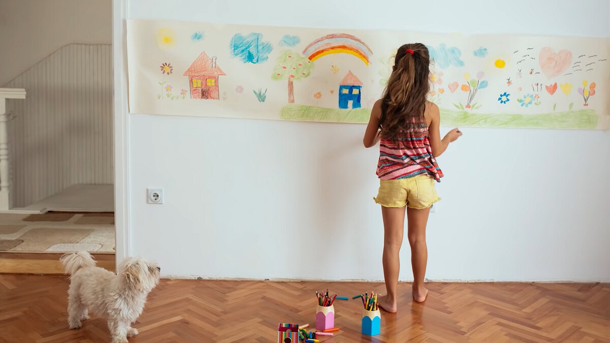 girl drawing pictures on butcher paper taped to wall