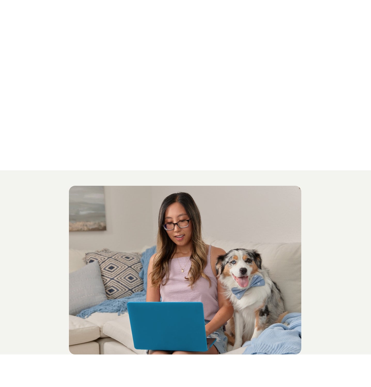 A TurboTax customer on her laptop sitting next to her dog on a couch.