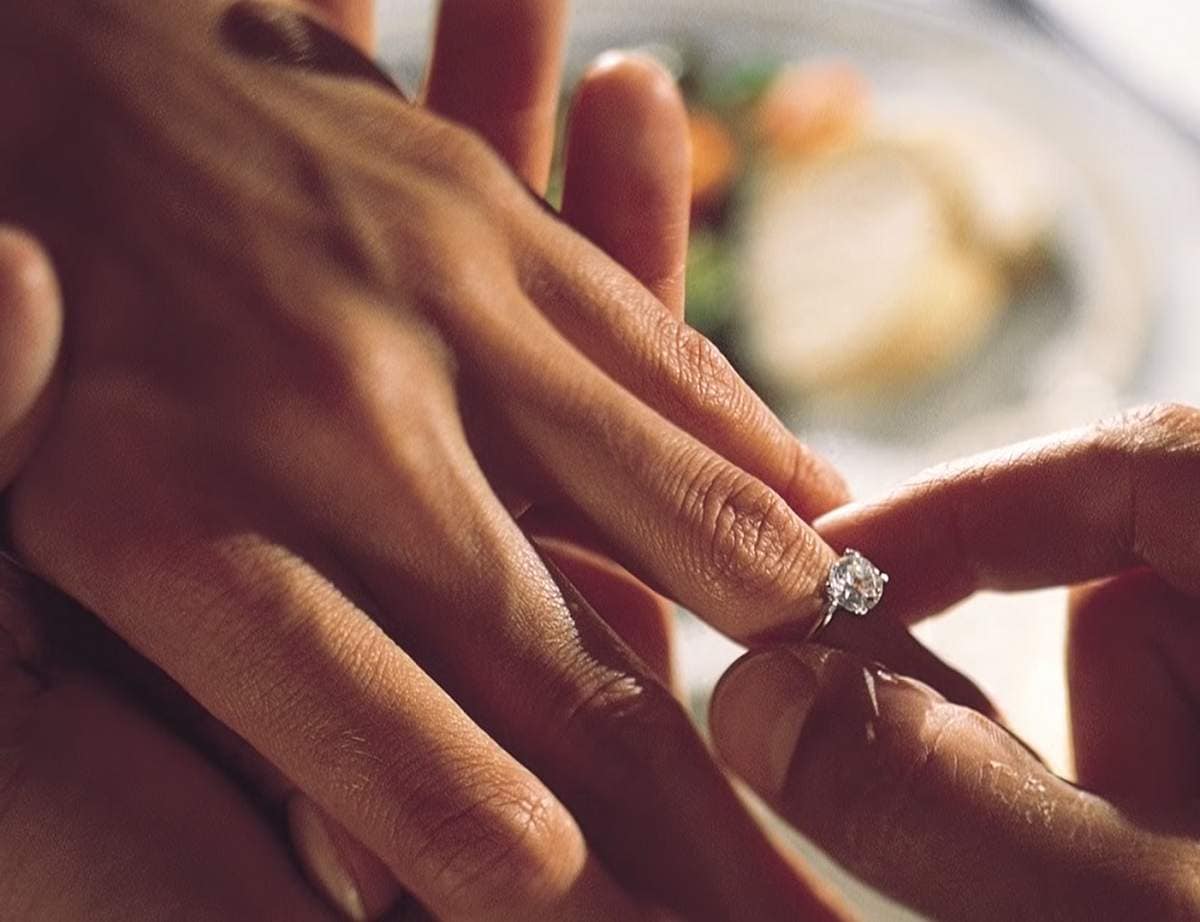 close-up of a person putting an engagement ring on a hand