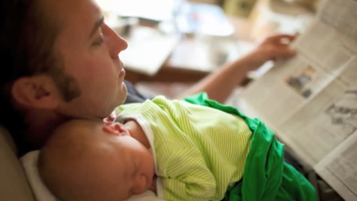 young dad with infant asleep on his shoulder