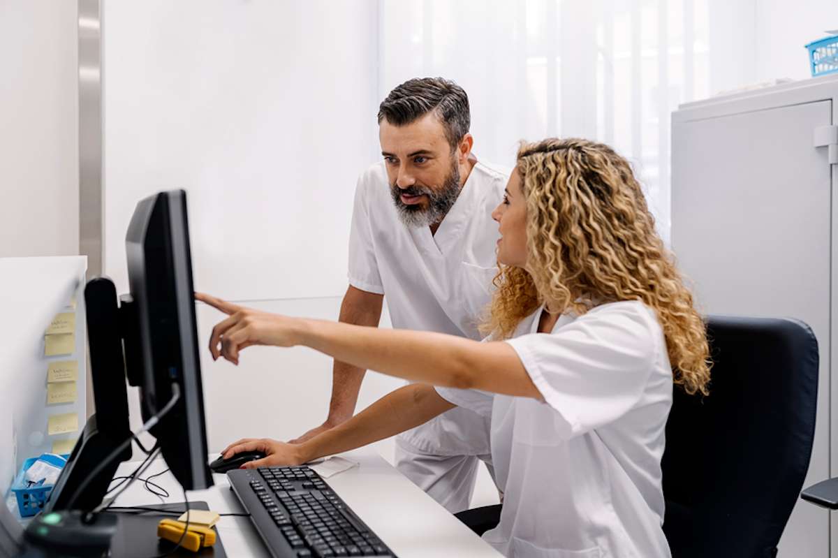 Two members of medical staff work at a computer in a hospital