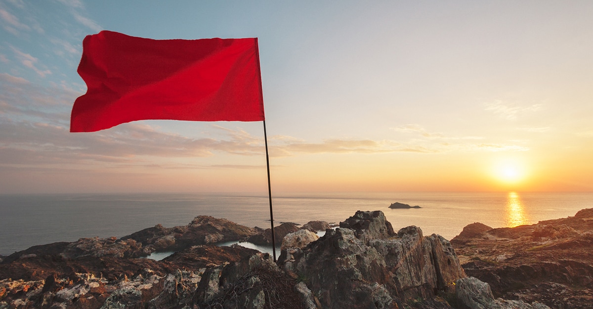 Bandeira vermelha contra um pôr do sol oceânico