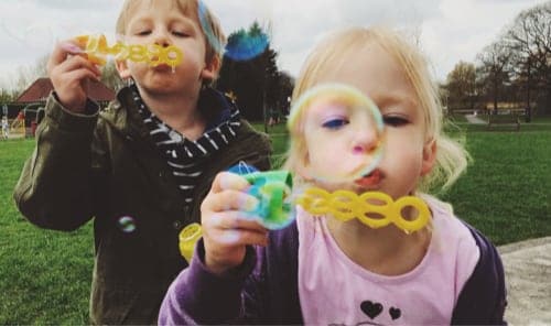 Two children blowing bubbles toward camera.