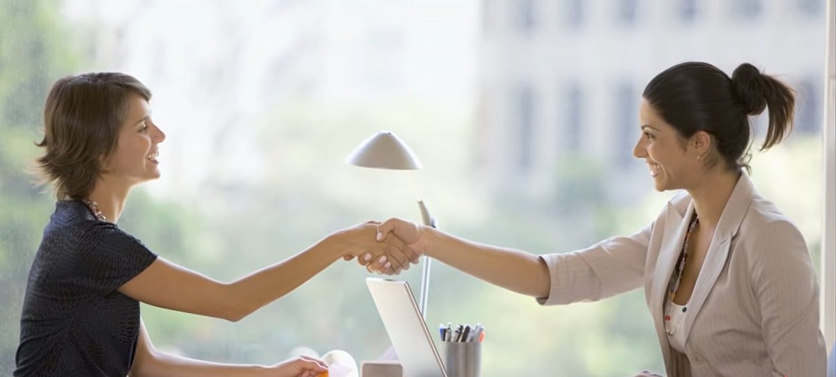 two women shaking hands over a desk