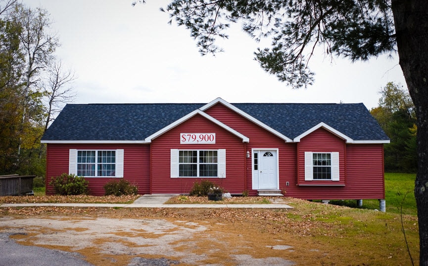 A single-level red home with a sign across the front that reads $79,900