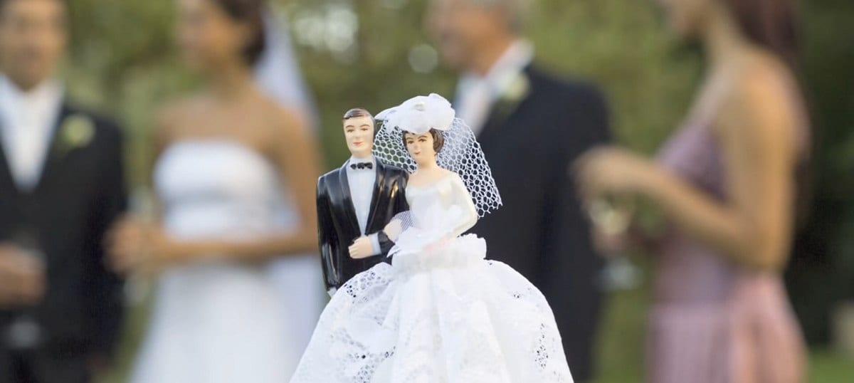 wedding cake topper with wedding party in background