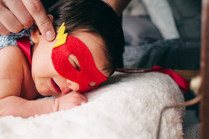 newborn infant sleeping with a hero mask on