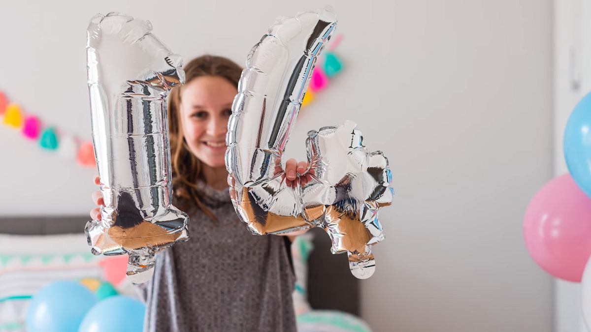 smiling teenage girl holding birthday balloons