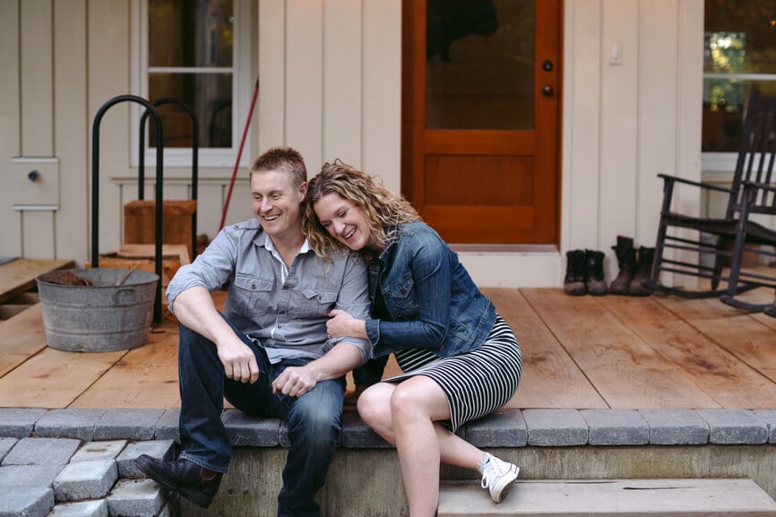 Happy expecting couple on their home's front porch.