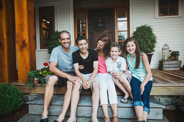 Young family of five posing on front porch