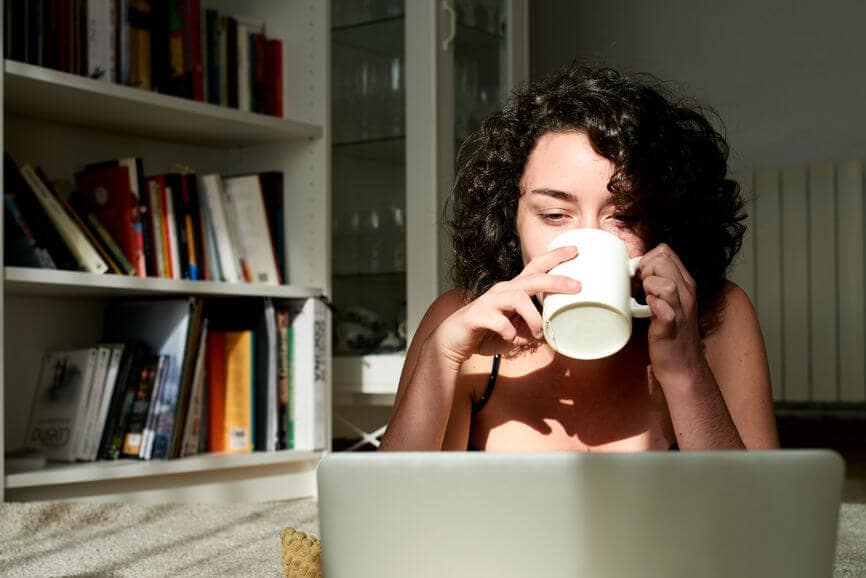 千禧一代女性一边喝咖啡一边用笔记本电脑工作