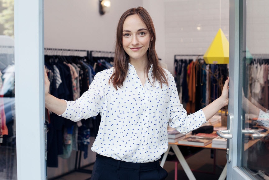 Smiling woman in the doorway of a clothing store