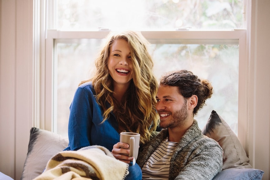 Happy couple on couch together after buying their first home.