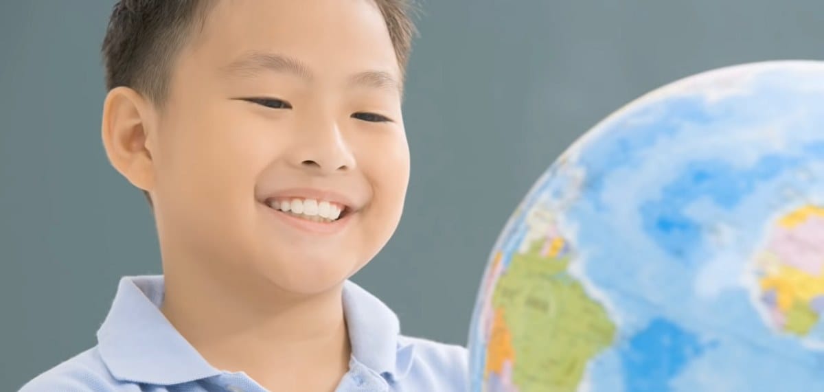 smiling boy looking at a globe