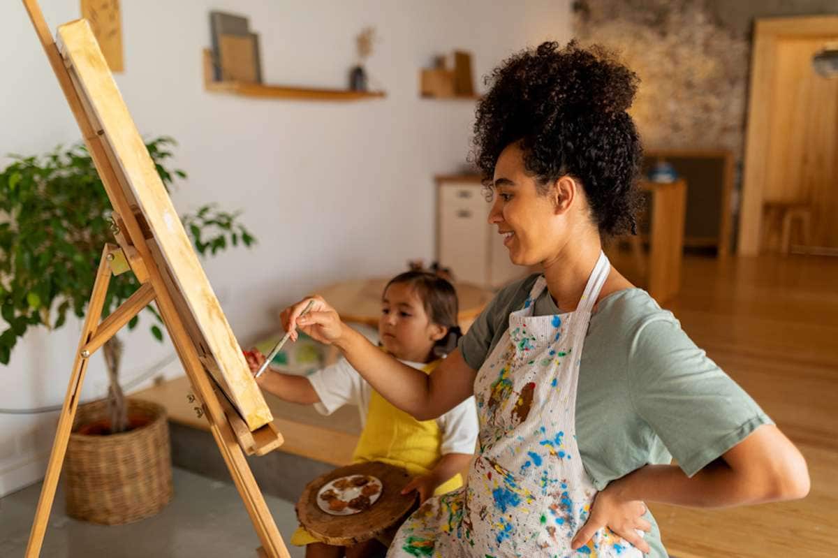 Una joven madre pinta sobre un lienzo con su hijo pequeño.