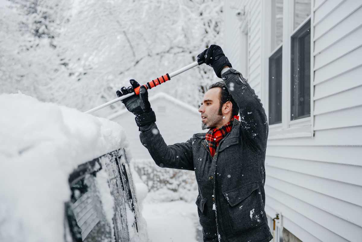 年轻人清理他的车经过一冬天的雪风暴