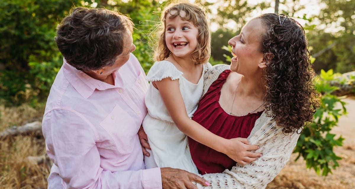 Grandmother and daughter are hugging a smiling young girl