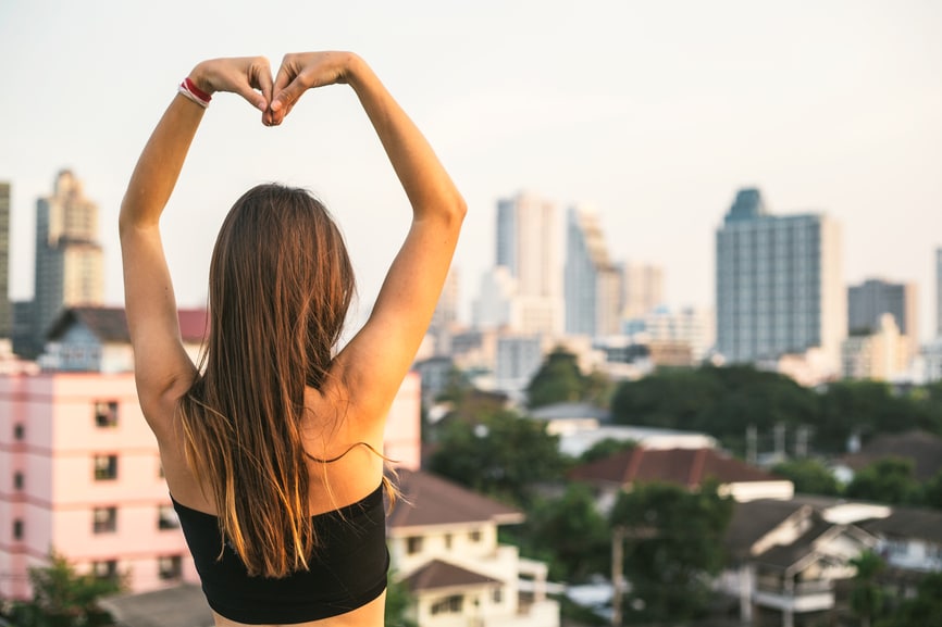 Woman making a heart shape with her arms.