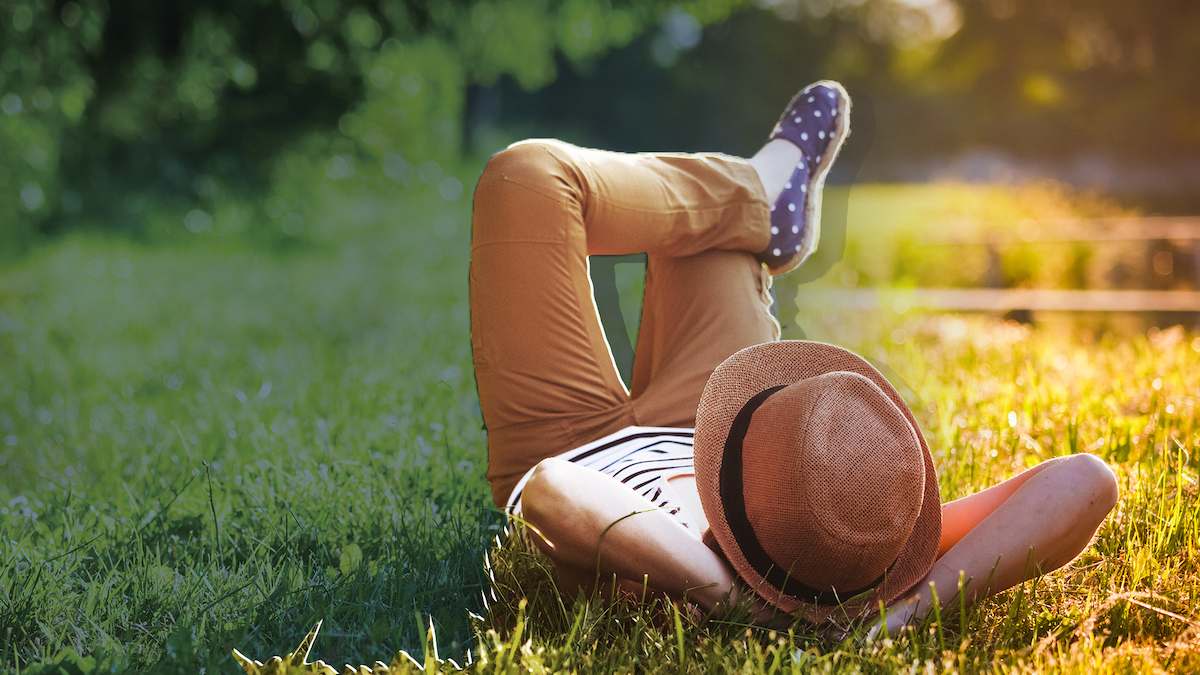 person in hat lying on grass