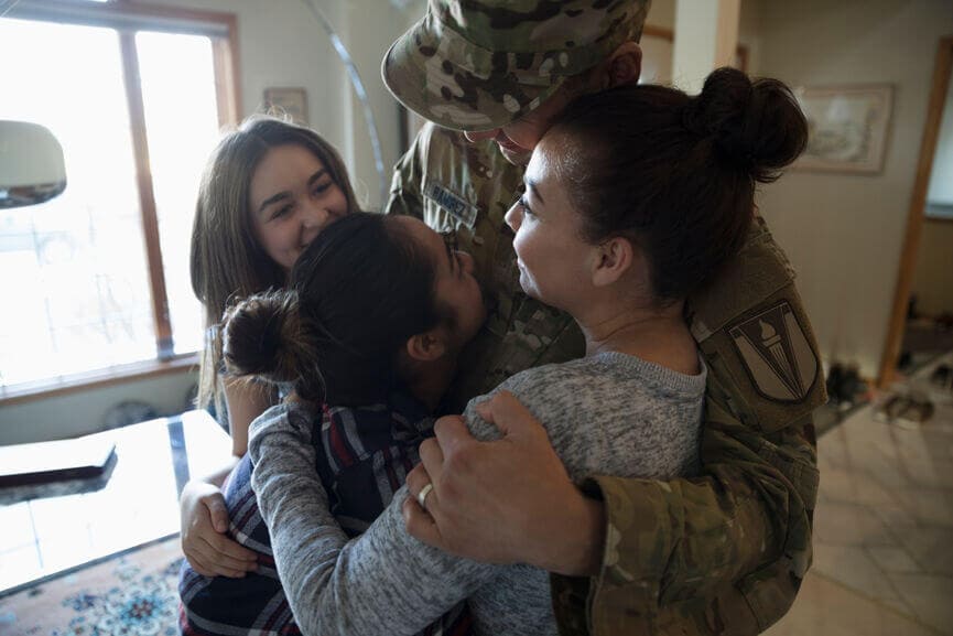 member of the armed services hugging his daughters