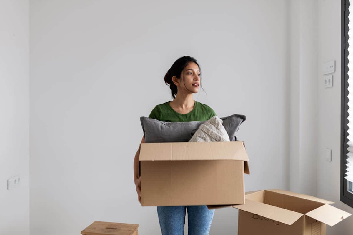 A woman carries a moving box.