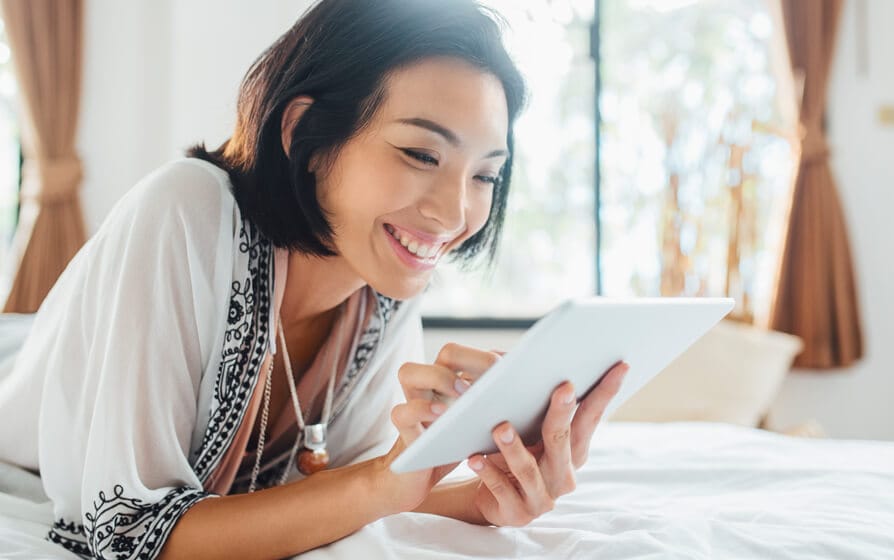 Smiling woman discovering her unclaimed tax refund on her tablet.