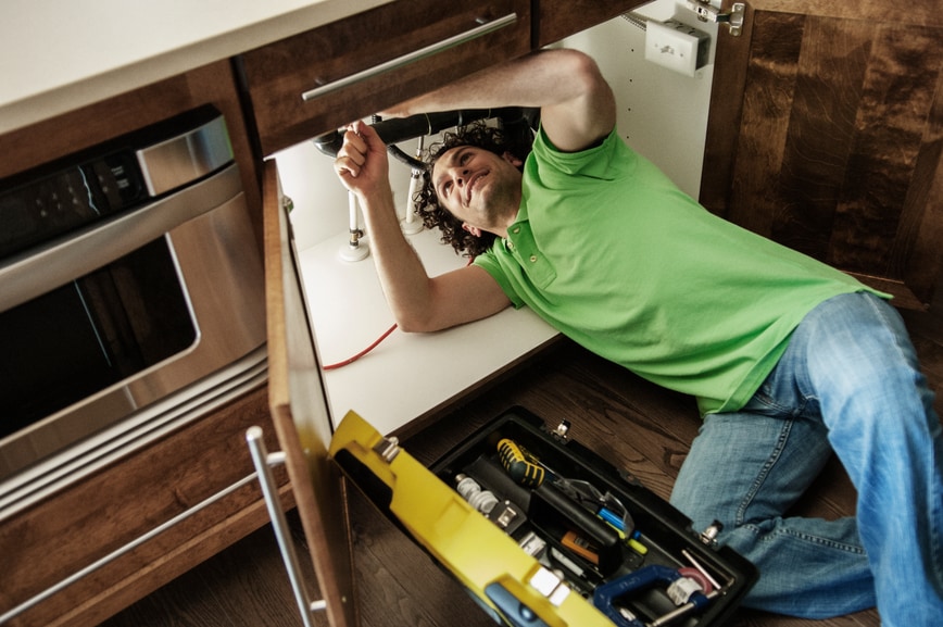 Handyman working on kitchen plumbing