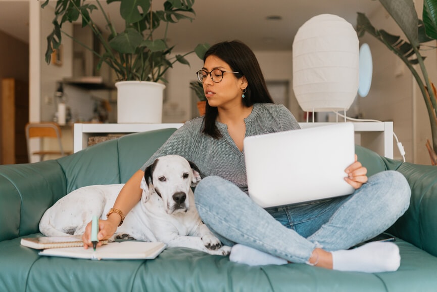 Woman sitting next to her dog on the couch and filing for a tax extension.